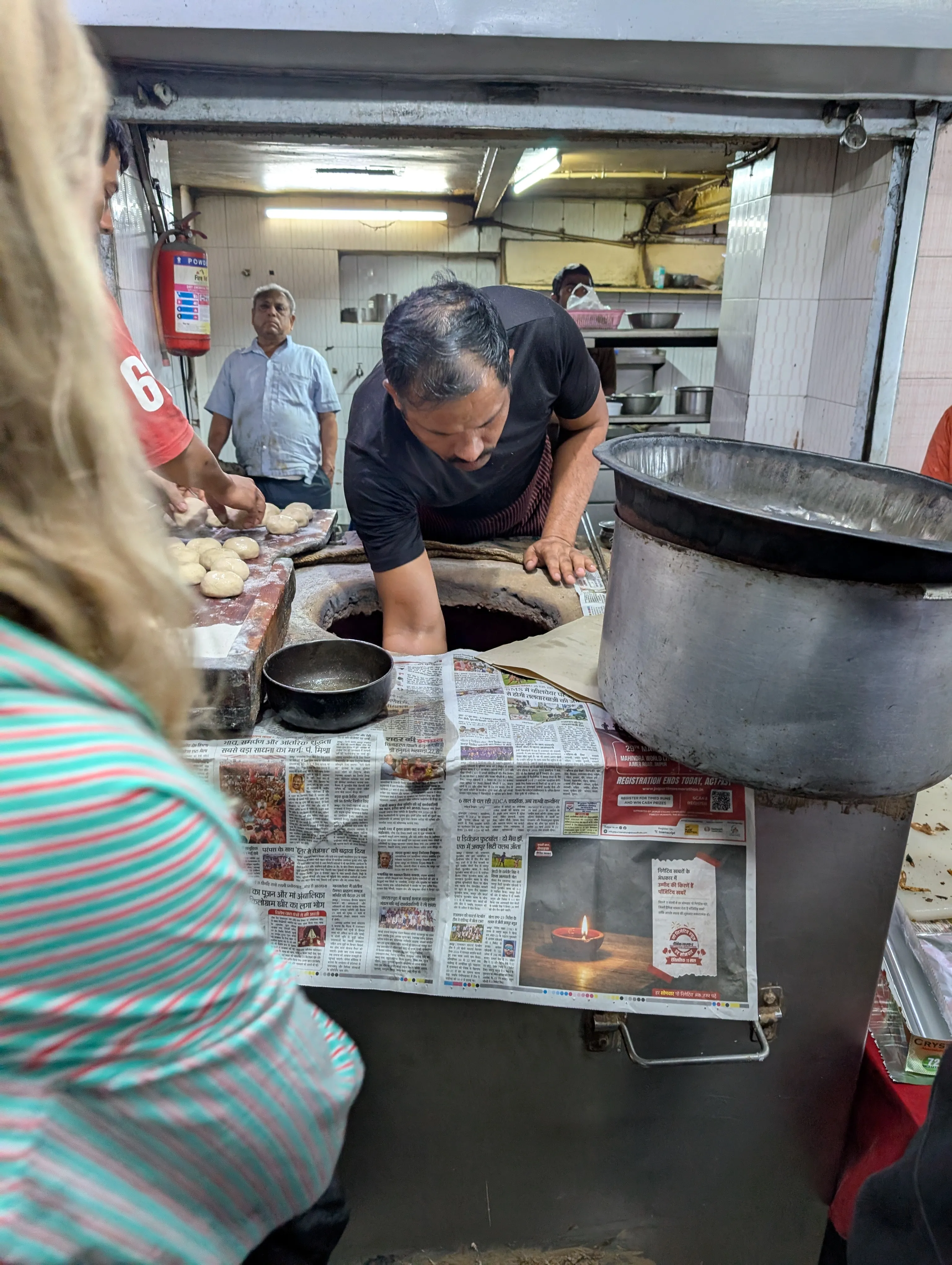 A baker pulling bread from a tandoor at a Jaipur street stall.